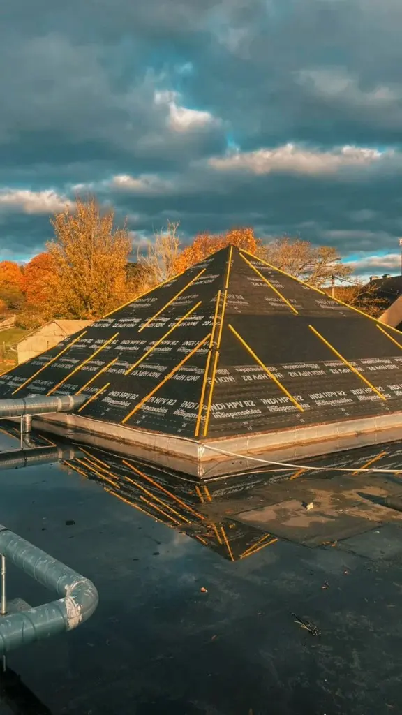 Toiture pyramidale en cours, membrane noire et liteaux jaunes